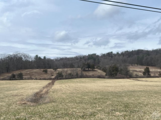view of grassy yard with a view of countryside and a view of trees