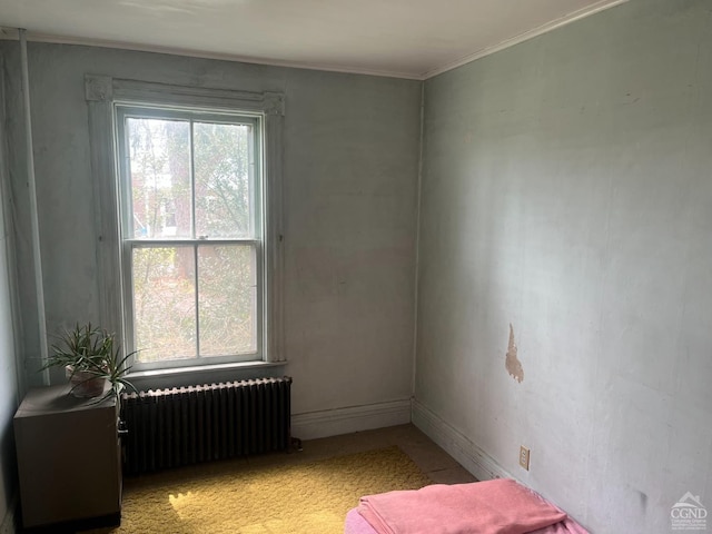 empty room with radiator heating unit, crown molding, and baseboards