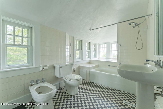 bathroom with separate shower and tub, a bidet, vaulted ceiling, toilet, and tile walls