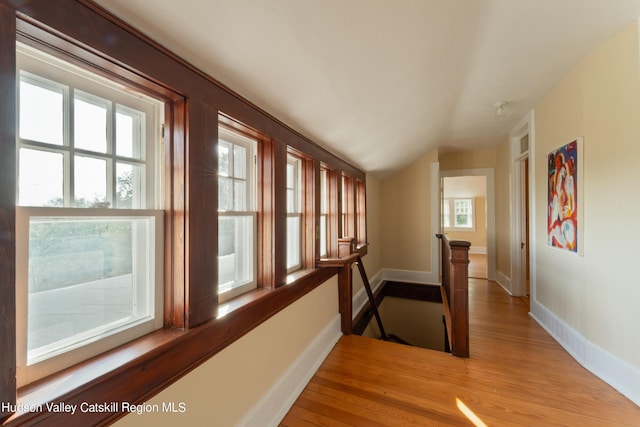 corridor with light hardwood / wood-style flooring and lofted ceiling