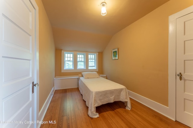 bedroom with light hardwood / wood-style floors and lofted ceiling