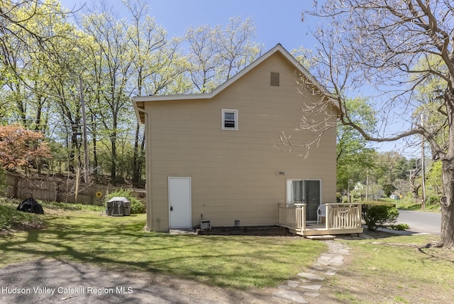 back of house featuring a wooden deck, a yard, and fence