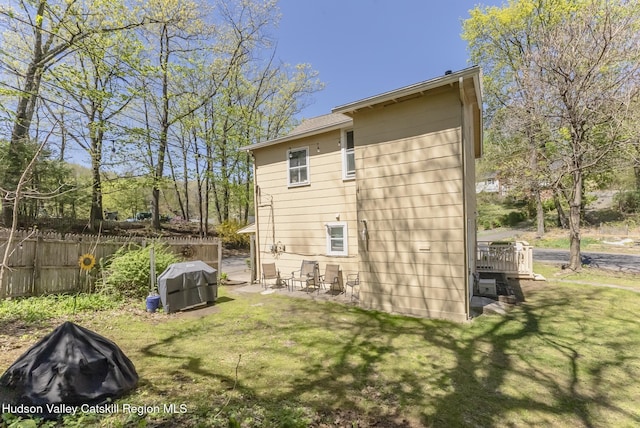 back of property featuring a lawn, a patio, and fence