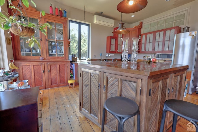 380 Main St, New Baltimore, NY 12124 - kitchen featuring appliances with stainless steel finishes, an AC wall unit, light wood-type flooring, glass insert cabinets, and hanging light fixtures