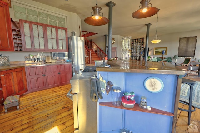 380 Main St, New Baltimore, NY 12124 - kitchen with appliances with stainless steel finishes, light wood-style flooring, a breakfast bar area, pendant lighting, and glass insert cabinets