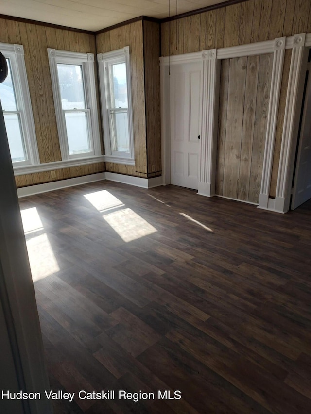 unfurnished bedroom with dark hardwood / wood-style floors and wooden walls