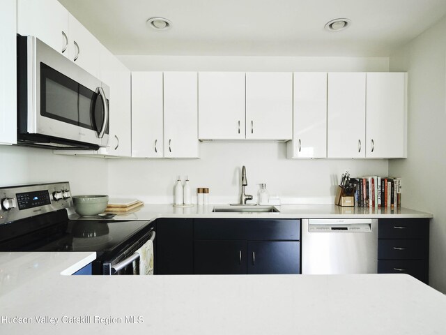 kitchen with appliances with stainless steel finishes, white cabinetry, and sink