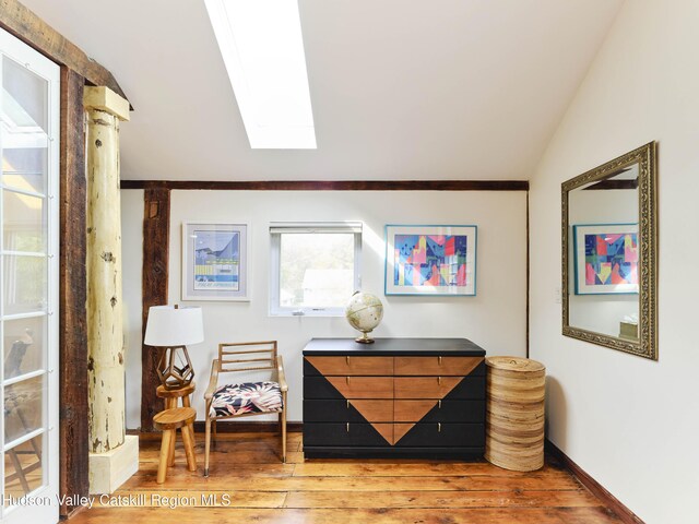 living area featuring wood-type flooring and lofted ceiling with skylight