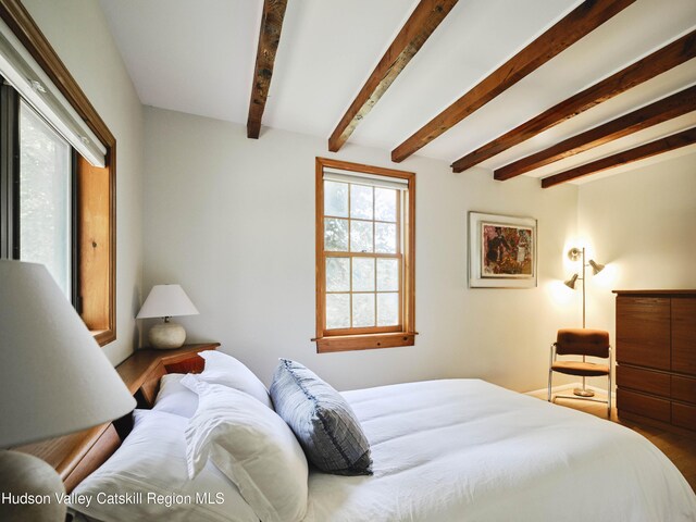 bedroom featuring beamed ceiling and hardwood / wood-style floors