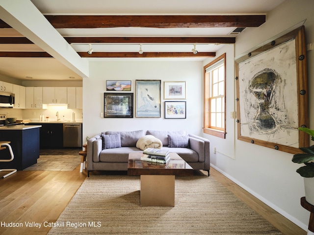 living room featuring hardwood / wood-style flooring, beam ceiling, and sink