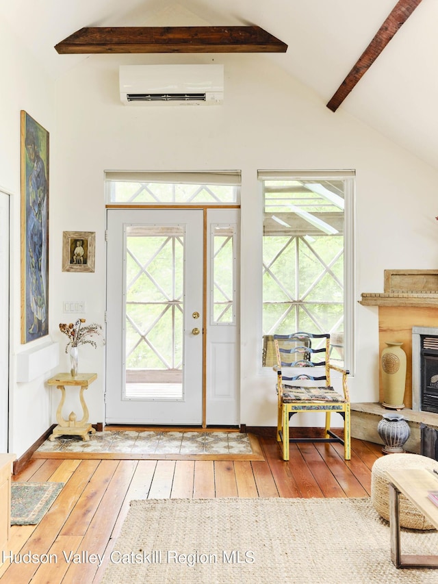 foyer entrance with vaulted ceiling with beams, light hardwood / wood-style floors, and an AC wall unit