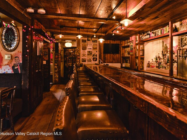 bar featuring wooden ceiling, wooden walls, beamed ceiling, and dark wood-type flooring