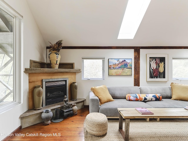 living room featuring vaulted ceiling with skylight and wood-type flooring