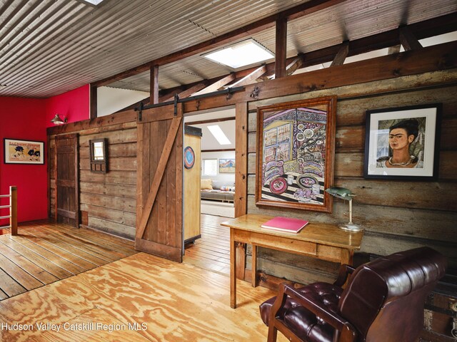 interior space featuring hardwood / wood-style floors, a barn door, and lofted ceiling