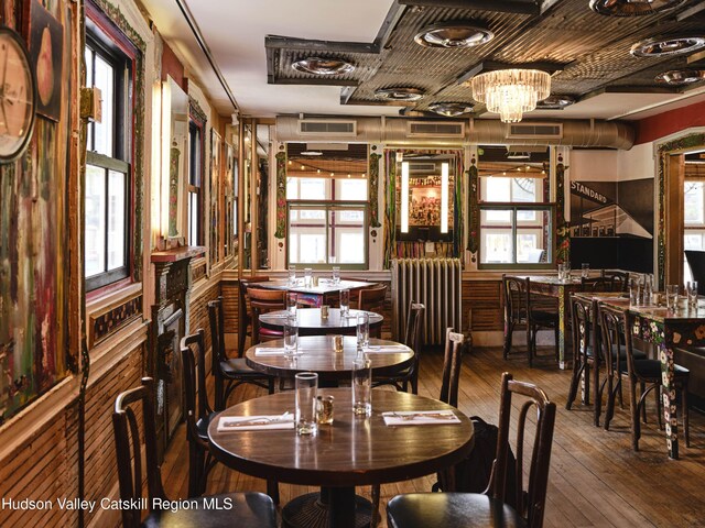 dining space featuring a chandelier, radiator heating unit, hardwood / wood-style flooring, and a healthy amount of sunlight