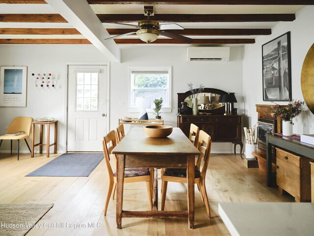 dining room with beamed ceiling, light hardwood / wood-style floors, and an AC wall unit