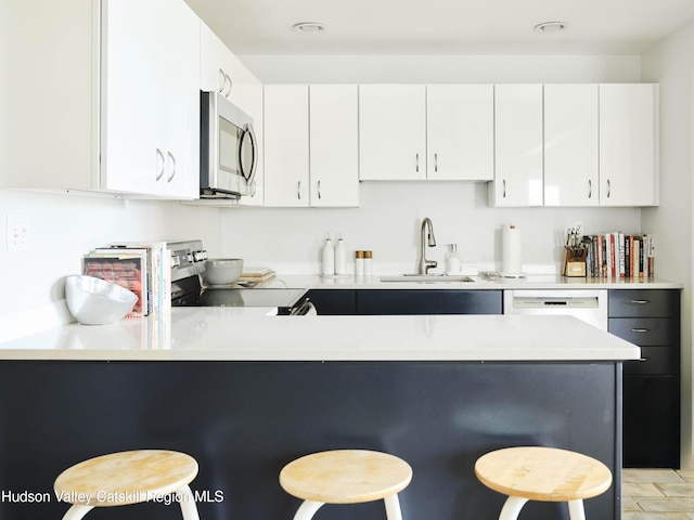 kitchen featuring a kitchen breakfast bar, sink, white cabinets, and stainless steel appliances