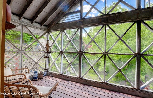 unfurnished sunroom featuring vaulted ceiling with beams and plenty of natural light