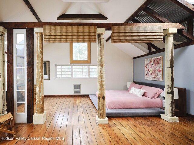 bedroom featuring hardwood / wood-style floors, lofted ceiling with beams, and multiple windows