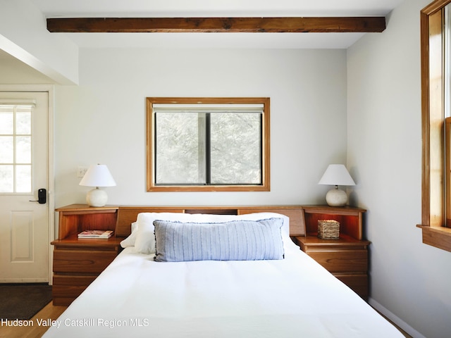 bedroom with hardwood / wood-style floors and beam ceiling