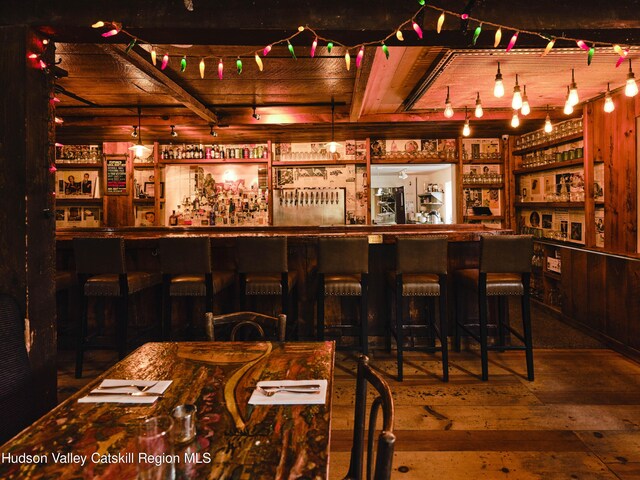 bar featuring pendant lighting, beamed ceiling, and dark wood-type flooring