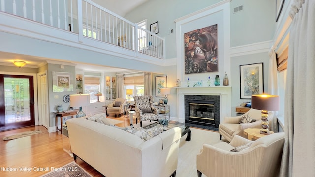 50 Manhattoes Dr, Athens, NY 12015 - living room featuring a fireplace with flush hearth, a towering ceiling, wood finished floors, and crown molding