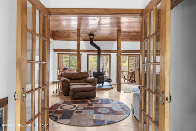 living area with wood ceiling, a wood stove, french doors, and wood finished floors
