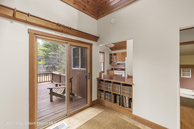 doorway featuring hardwood / wood-style floors, visible vents, and a towering ceiling