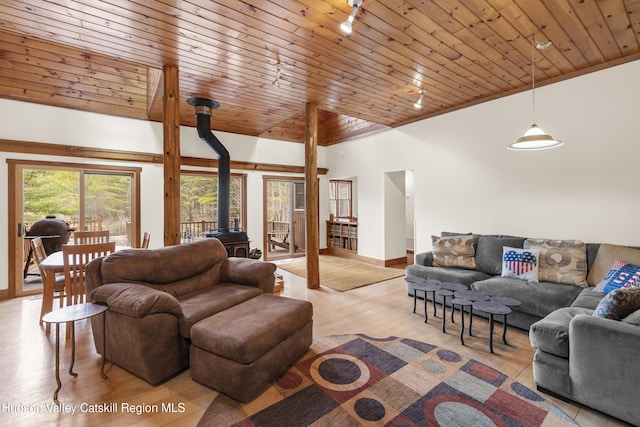 living room featuring wood ceiling, baseboards, light wood-style floors, and a wood stove