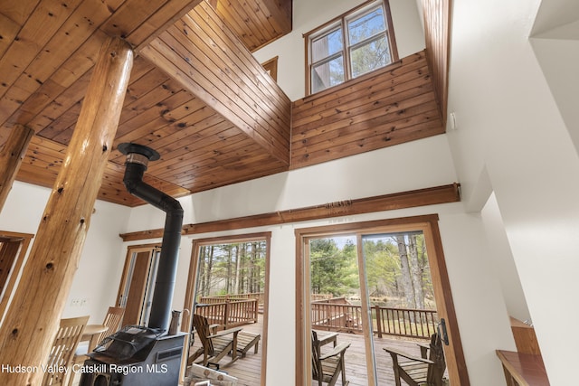 interior space featuring a high ceiling, a healthy amount of sunlight, and a wood stove