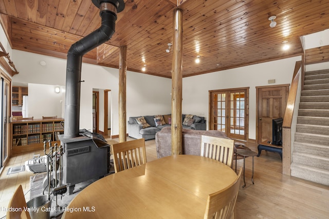 dining room with french doors, wood finished floors, stairs, wood ceiling, and a wood stove