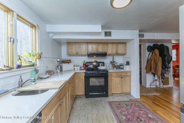 kitchen with visible vents, a sink, tasteful backsplash, range hood, and black range with gas stovetop