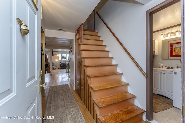 stairs with wood finished floors and visible vents