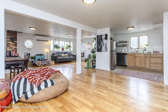 living room featuring light wood-type flooring and a wall unit AC