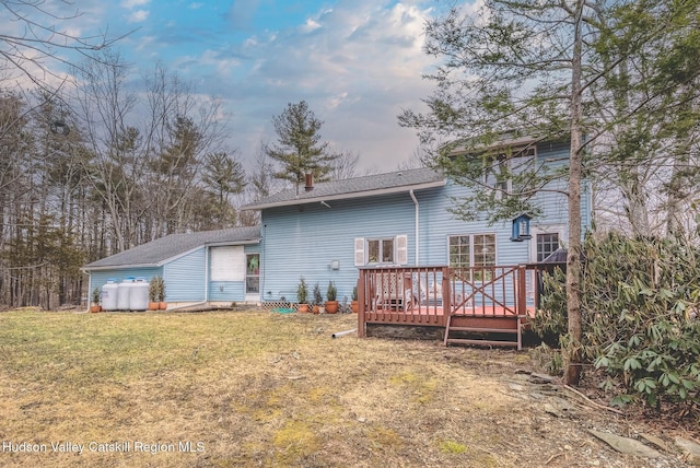 back of house featuring a lawn and a wooden deck