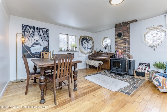 dining area with a wealth of natural light, a wood stove, and wood finished floors