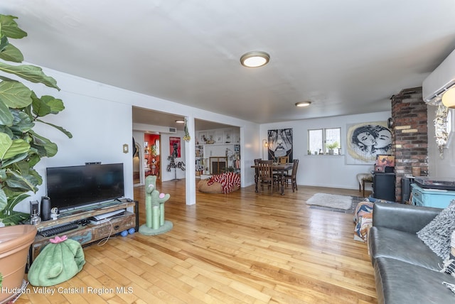 living area featuring an AC wall unit and wood finished floors