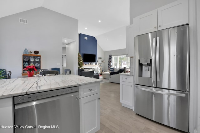 kitchen with light stone countertops, white cabinetry, light hardwood / wood-style flooring, and stainless steel appliances