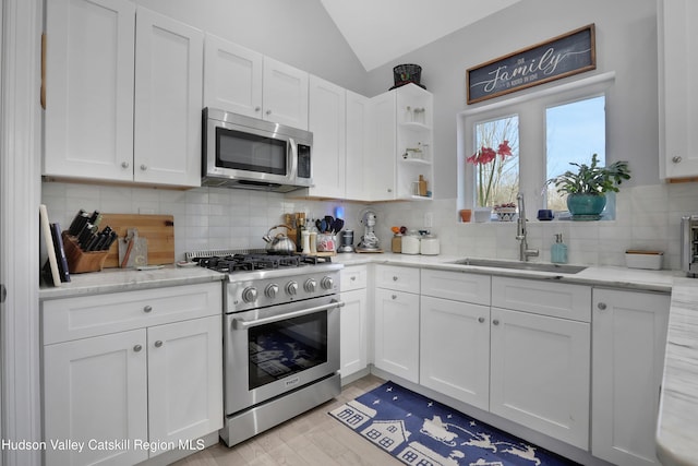 kitchen with white cabinets, sink, lofted ceiling, and stainless steel appliances