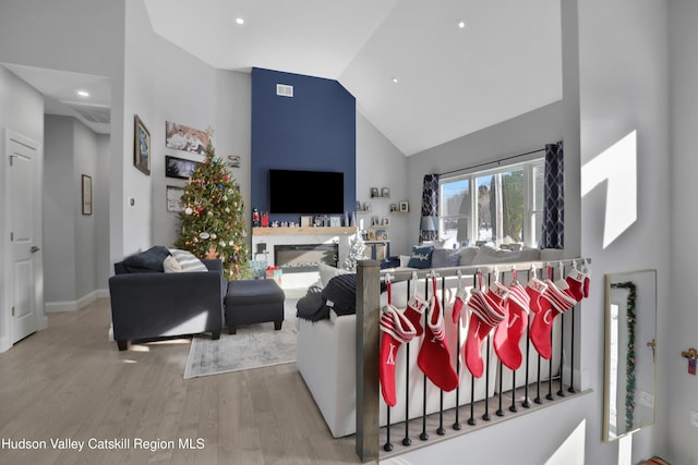 living room featuring hardwood / wood-style flooring, a premium fireplace, and high vaulted ceiling