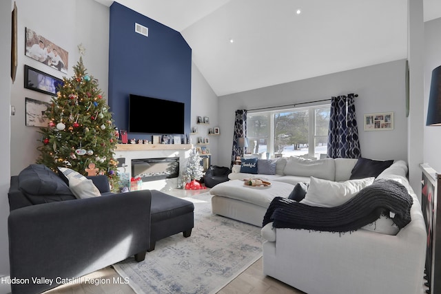 living room featuring light wood-type flooring and high vaulted ceiling