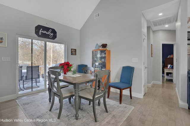 dining area featuring light hardwood / wood-style flooring and high vaulted ceiling