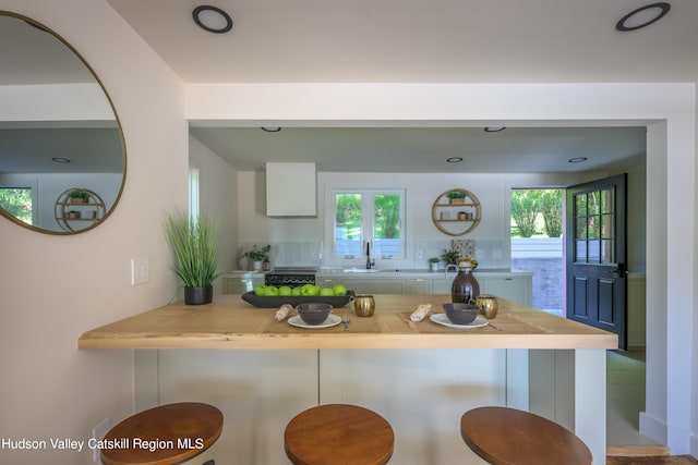 kitchen featuring decorative backsplash, kitchen peninsula, a breakfast bar area, and a wealth of natural light