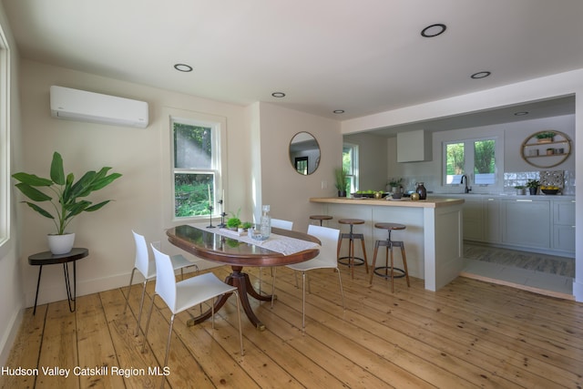 dining room featuring sink, a wall mounted air conditioner, and light wood-type flooring