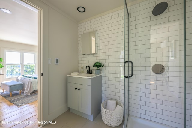 bathroom featuring a shower with door, vanity, wood-type flooring, and ornamental molding