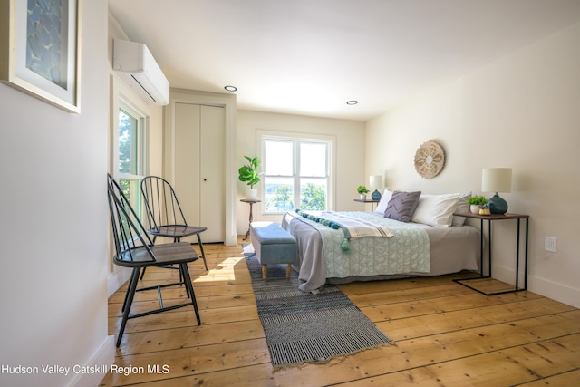 bedroom with a wall mounted air conditioner and light wood-type flooring