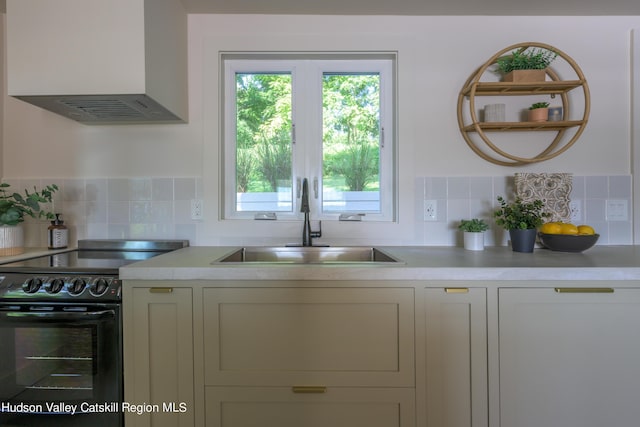 kitchen with decorative backsplash, wall chimney range hood, sink, and black range with electric cooktop