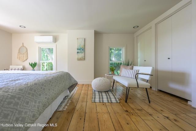 bedroom with light hardwood / wood-style floors and a wall mounted AC