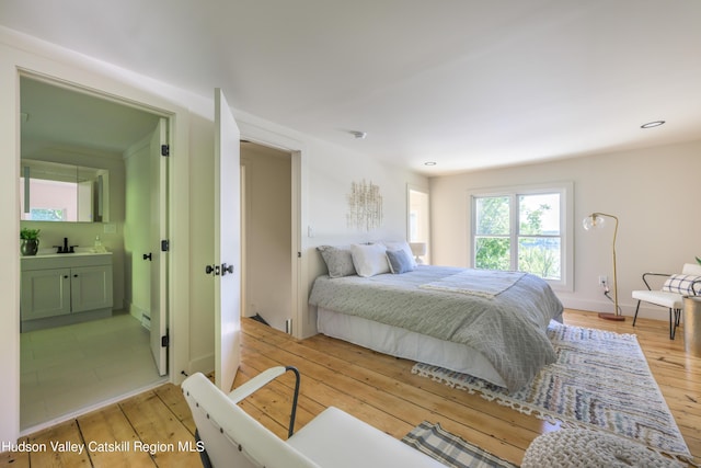 bedroom featuring light wood-type flooring and connected bathroom