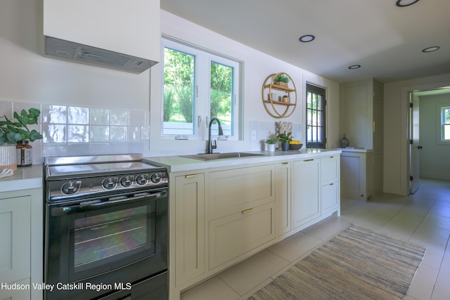 kitchen featuring light tile patterned flooring, black range with electric stovetop, plenty of natural light, and sink